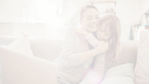 mother hugging daughter and holding laptop computer