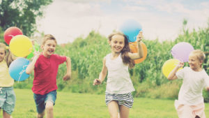 Children running in a field with balloons