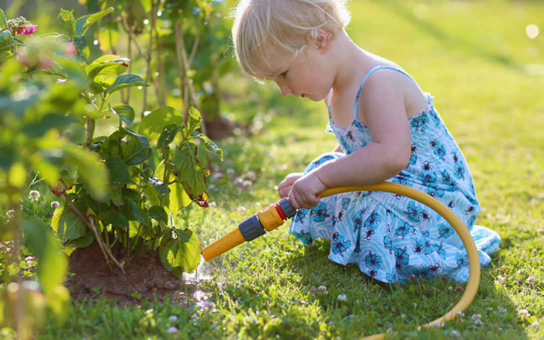 little girl watering flowers with hose