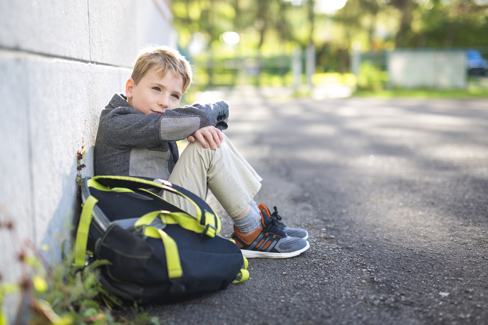 Young boy waiting outside of school