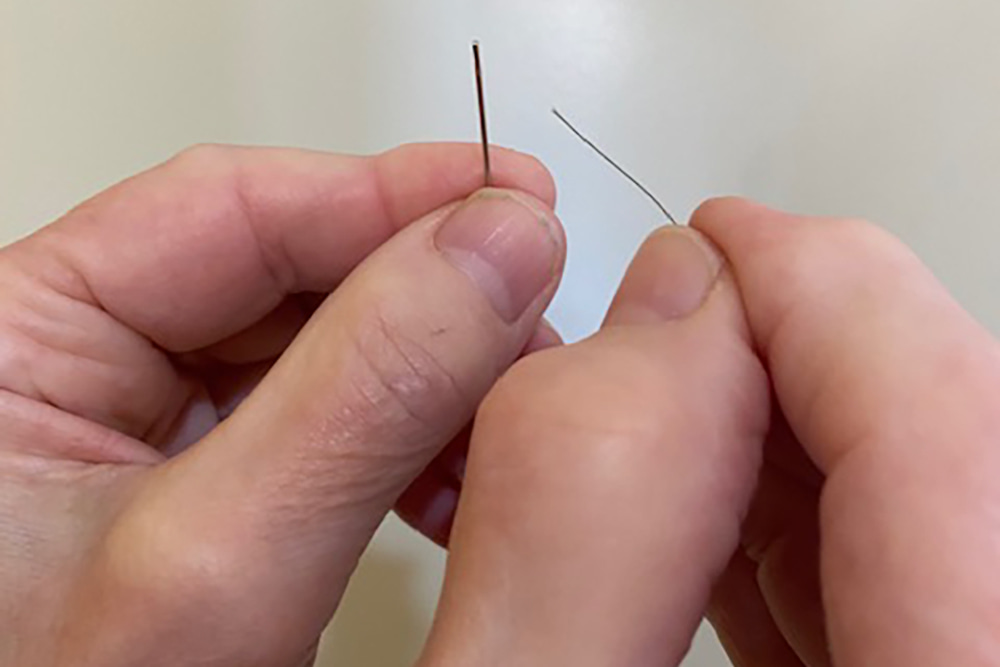 hands threading a needle