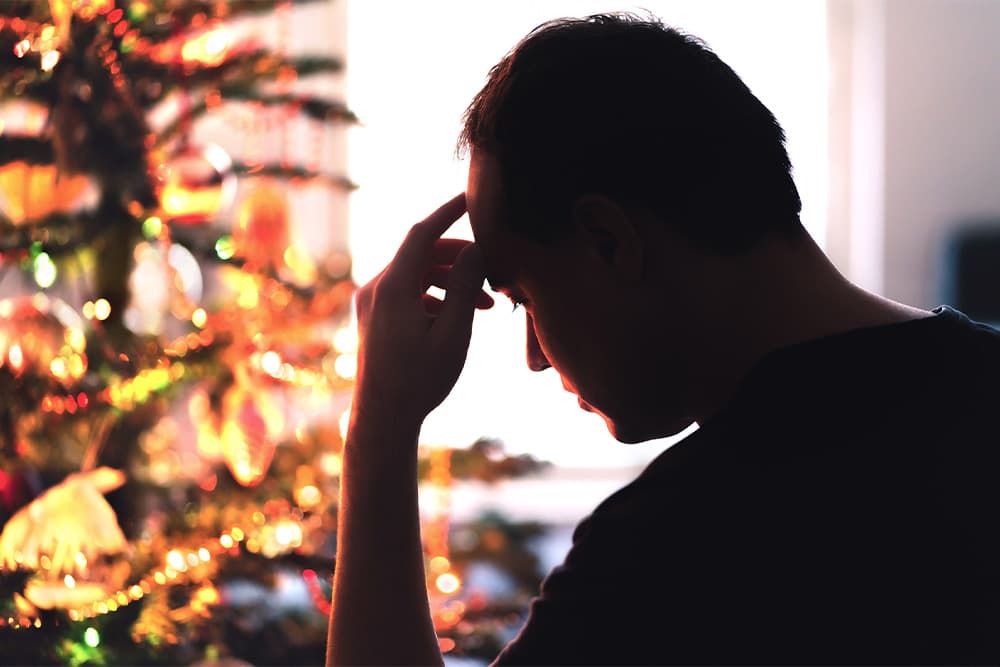 man-sits-in-front-of-christmas-tree
