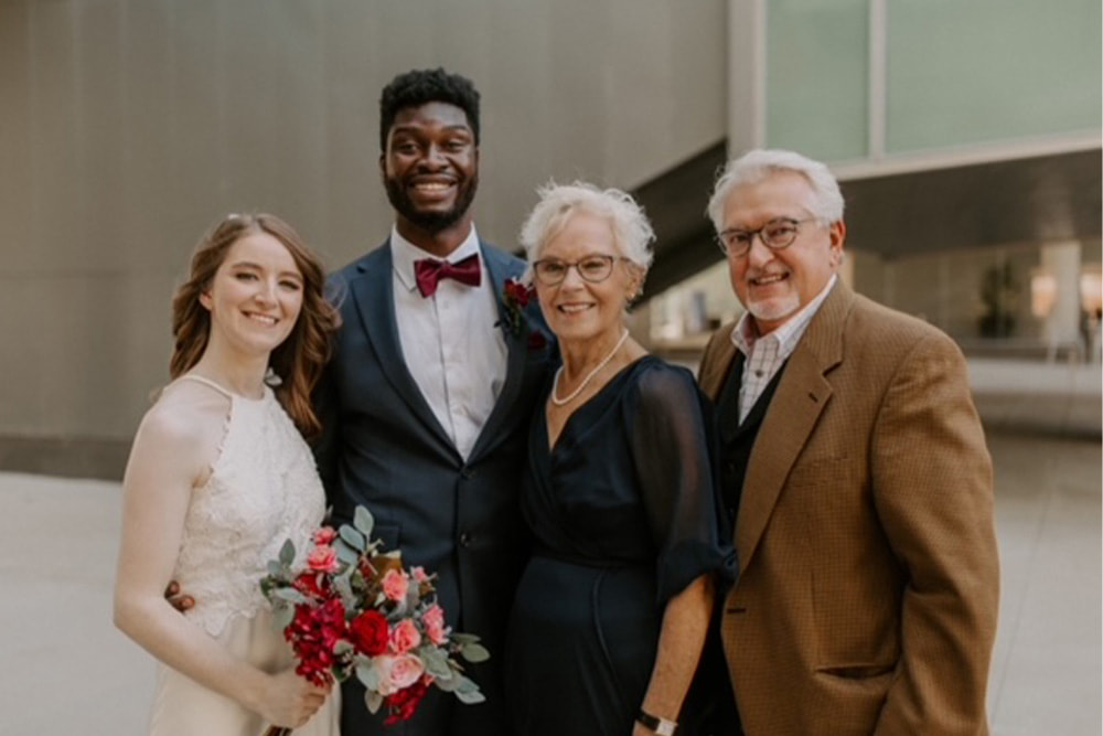 groom and bride smiling for photo with senior couple in front of Holland Center in Omaha