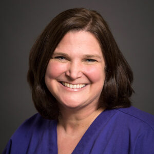Headshot of Laura Corbridge wearing blue top on gray background