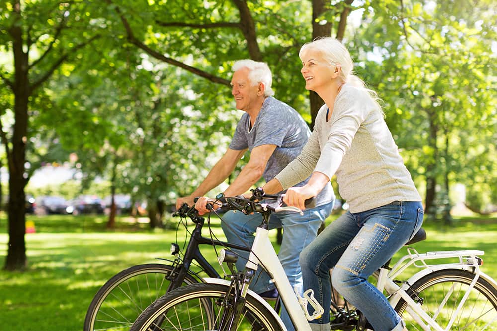 older couple riding bikes in the park