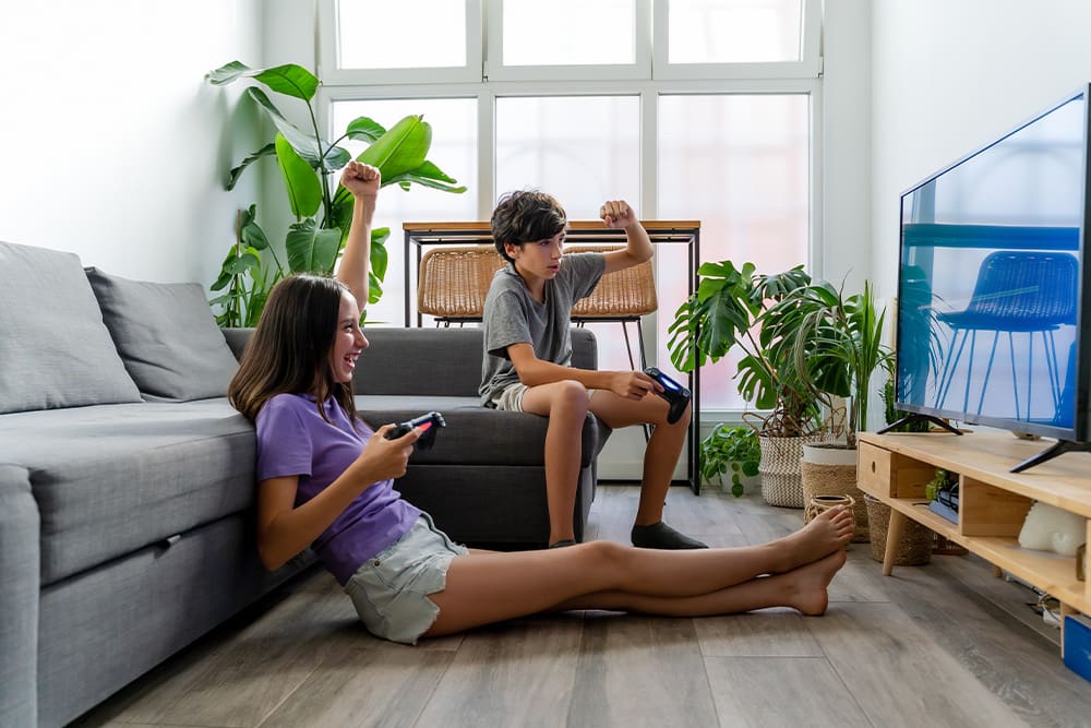 Brother and sister playing video games together in living room cheering