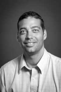 Black and white headshot of man with short hair wearing button up