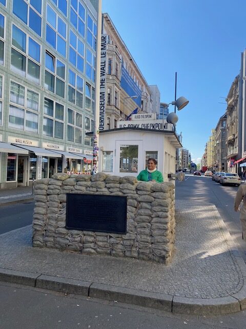 Woman standing behind sandbag wall at the Checkpoint Charlie Museum in Berlin, Germany