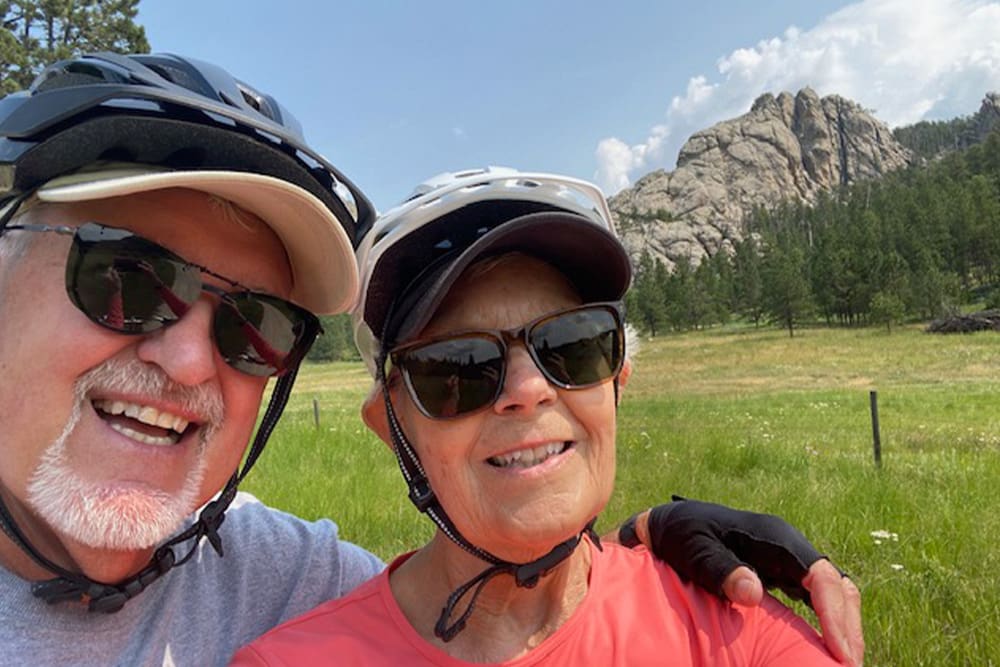 Nancy and husband John smiling and wearing bike helmets and sunglasses while on ebike adventure