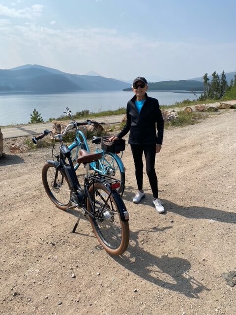 Nancy standing next to two ebikes with mountains in background